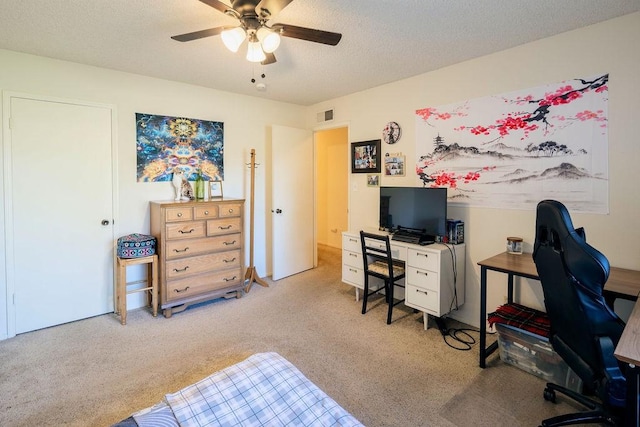 carpeted office featuring ceiling fan and a textured ceiling