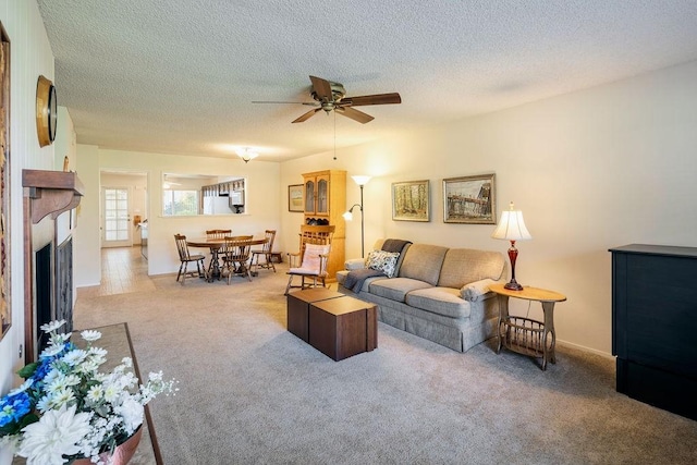 carpeted living room with ceiling fan and a textured ceiling