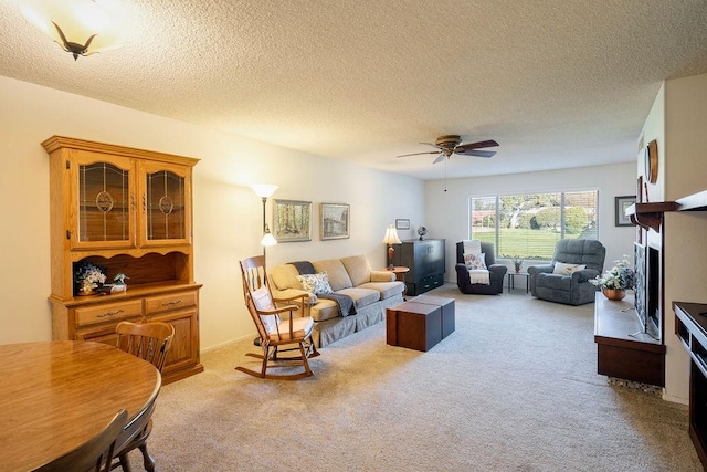 living room featuring ceiling fan, light colored carpet, and a textured ceiling