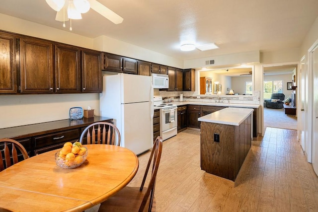 kitchen with white appliances, a center island, ceiling fan, and light hardwood / wood-style floors