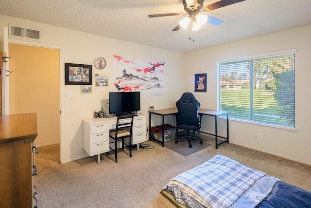 carpeted office space featuring ceiling fan and a textured ceiling