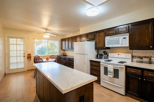 kitchen featuring dark brown cabinets, white appliances, ceiling fan, a center island, and light hardwood / wood-style floors