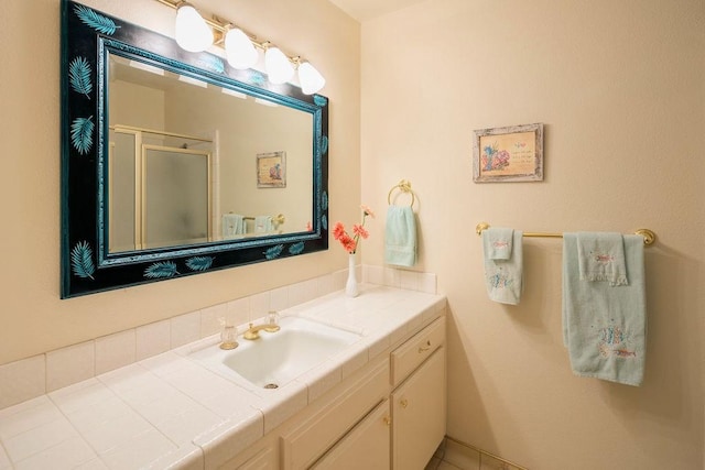 bathroom featuring a shower with door and vanity