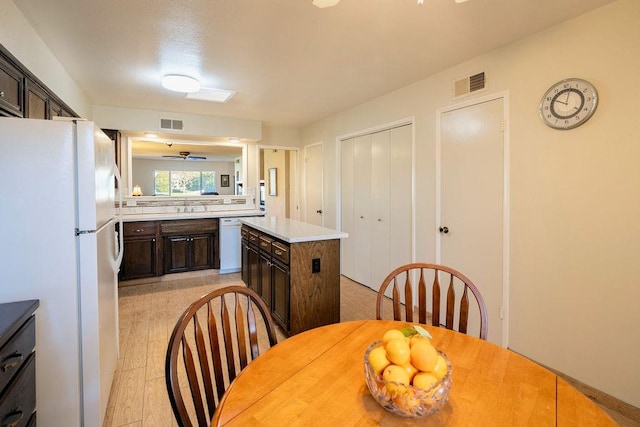 kitchen featuring dark brown cabinets, white appliances, a center island, and ceiling fan