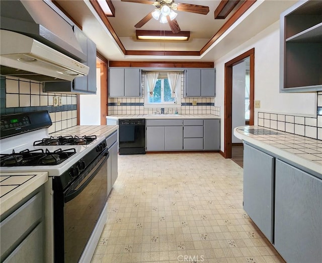 kitchen featuring exhaust hood, black dishwasher, a tray ceiling, range with gas stovetop, and gray cabinets