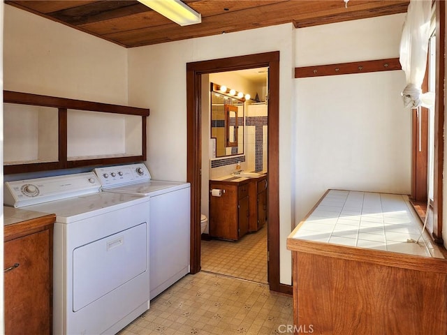 washroom featuring wooden ceiling, sink, and washing machine and clothes dryer