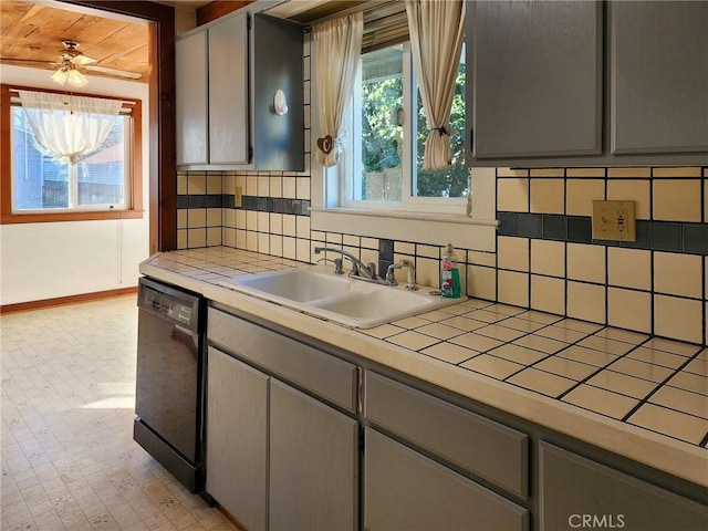 kitchen with tile counters, black dishwasher, sink, backsplash, and gray cabinets