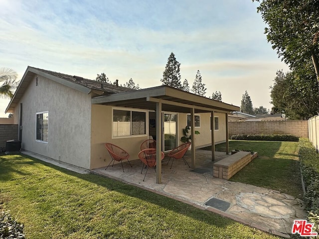 rear view of property featuring a patio area, a yard, and central AC