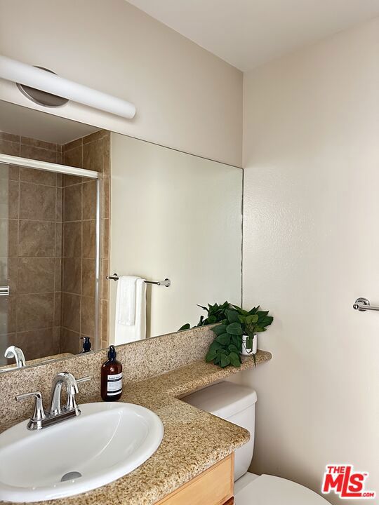 bathroom featuring vanity, toilet, and a shower with door