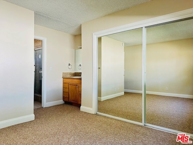 unfurnished bedroom featuring carpet flooring, connected bathroom, and a textured ceiling