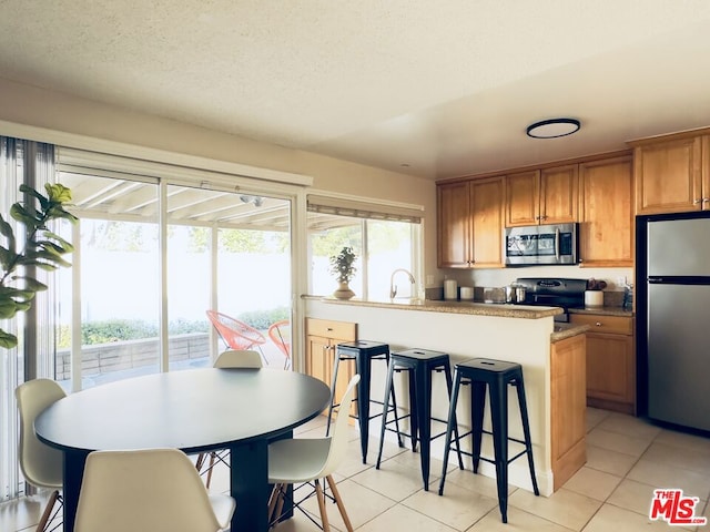 kitchen featuring sink, light tile patterned floors, a textured ceiling, and appliances with stainless steel finishes