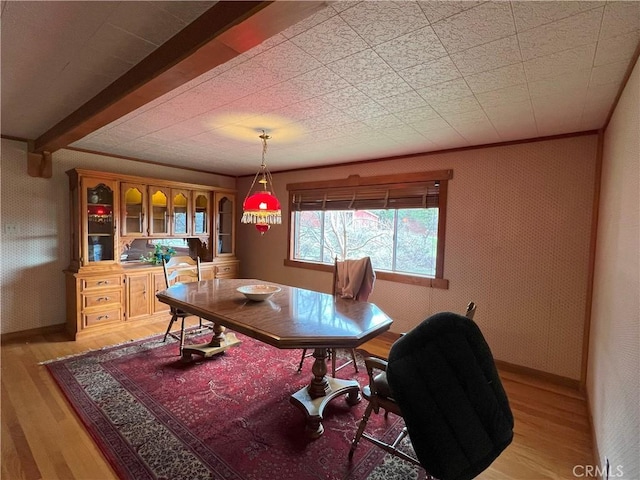 dining space featuring beam ceiling, light hardwood / wood-style floors, and crown molding