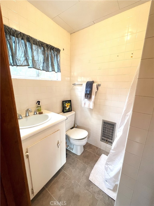 bathroom featuring tile patterned floors, vanity, toilet, and tile walls