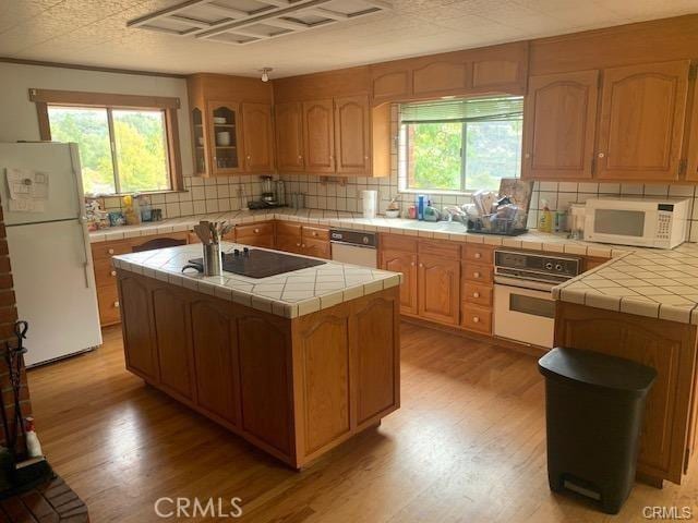 kitchen featuring tile countertops, white appliances, and a wealth of natural light