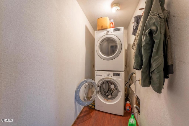 clothes washing area with dark hardwood / wood-style floors and stacked washer / drying machine