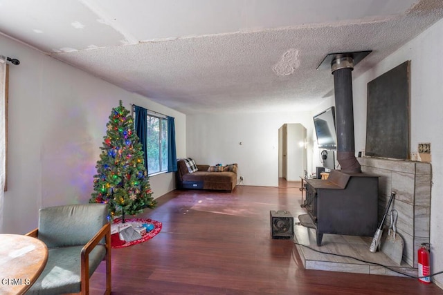 living room with a wood stove, wood finished floors, and a textured ceiling