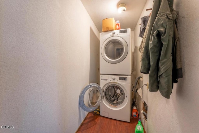 laundry room featuring wood finished floors, stacked washer / dryer, and laundry area