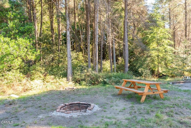 view of yard with an outdoor fire pit and a view of trees