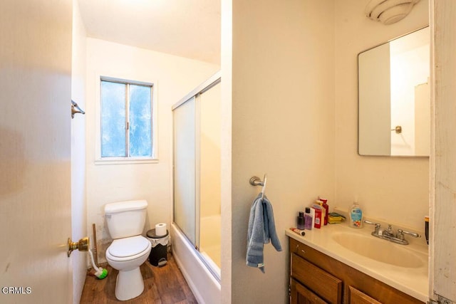 full bath featuring enclosed tub / shower combo, toilet, vanity, and wood finished floors