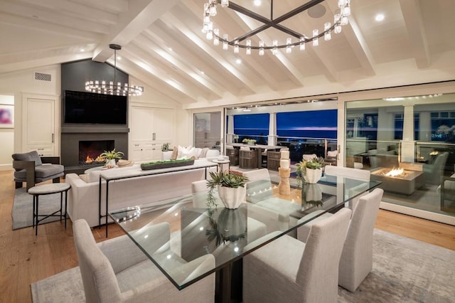 dining room with a large fireplace, light hardwood / wood-style flooring, and lofted ceiling with beams