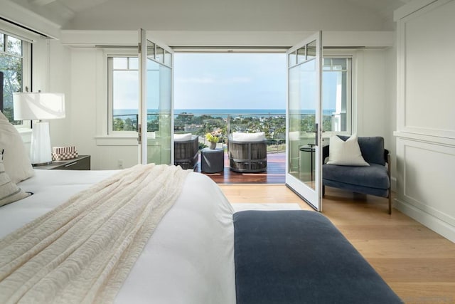 bedroom featuring multiple windows, a water view, and light wood-type flooring