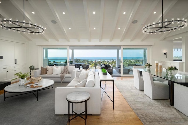 living room featuring a notable chandelier, light hardwood / wood-style floors, plenty of natural light, and lofted ceiling with beams