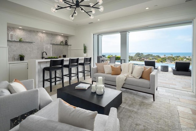 living room with a water view, plenty of natural light, a notable chandelier, and a tray ceiling