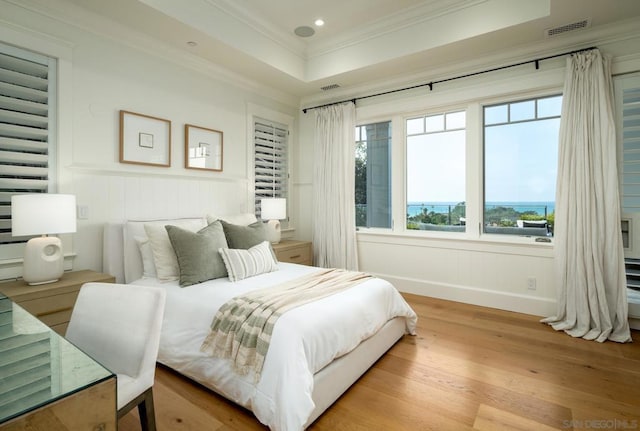 bedroom with a tray ceiling, crown molding, and light hardwood / wood-style floors