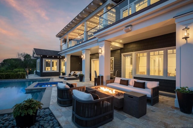 exterior space with a balcony, an outdoor living space with a fire pit, and a pool with hot tub