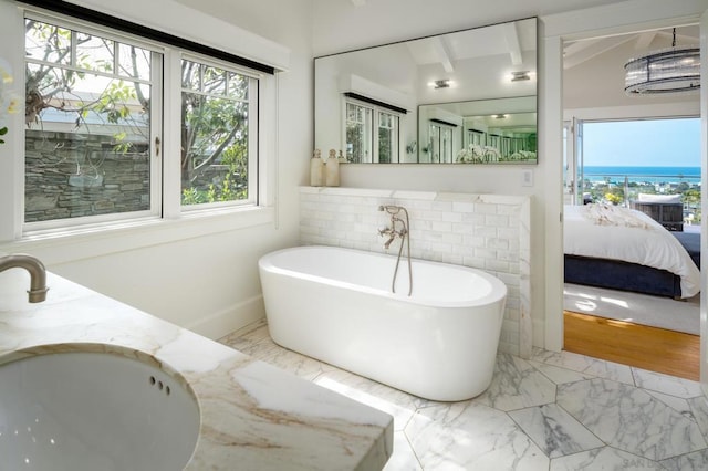 bathroom featuring a tub to relax in, a water view, sink, and beamed ceiling