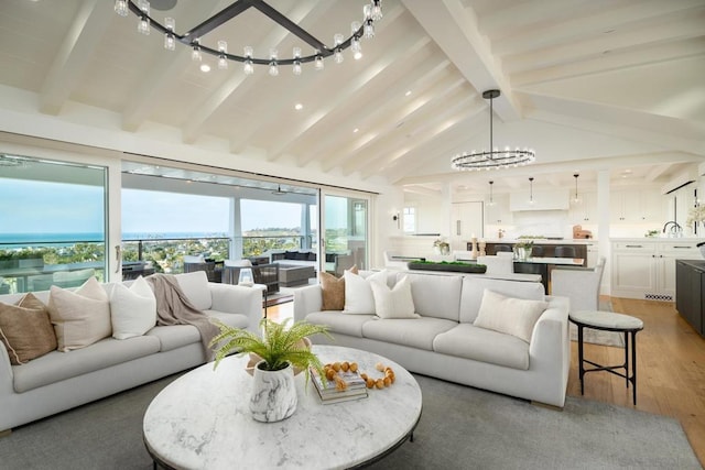 living room featuring lofted ceiling with beams, hardwood / wood-style flooring, and a notable chandelier