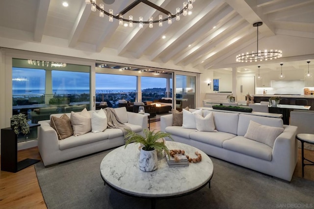 living room with lofted ceiling with beams, wood-type flooring, and an inviting chandelier