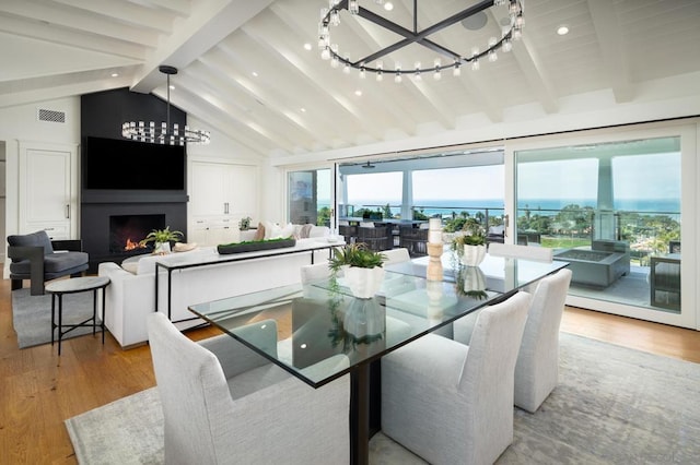 dining area featuring lofted ceiling with beams, a large fireplace, and light hardwood / wood-style floors