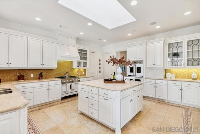 kitchen featuring white cabinetry, high end stainless steel range oven, and premium range hood