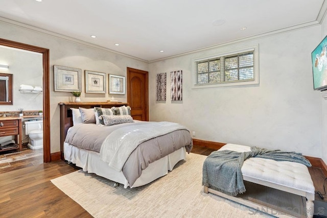 bedroom with connected bathroom, hardwood / wood-style flooring, and crown molding