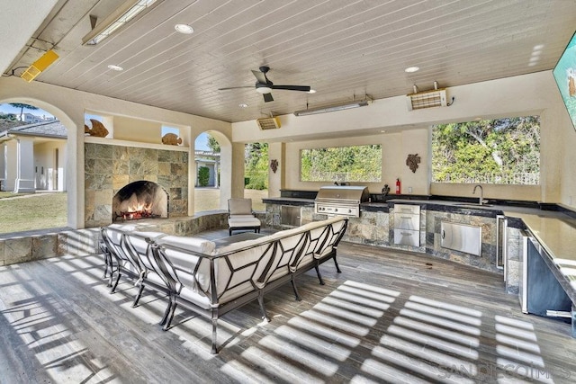 view of patio featuring ceiling fan, sink, an outdoor kitchen, an outdoor living space with a fireplace, and area for grilling