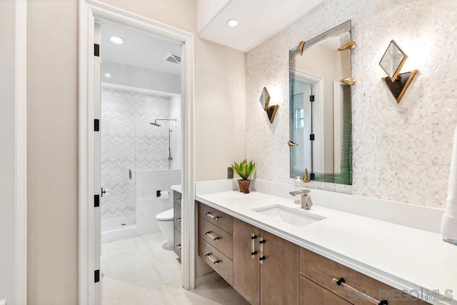 bathroom featuring tile patterned flooring, vanity, tiled shower, and toilet