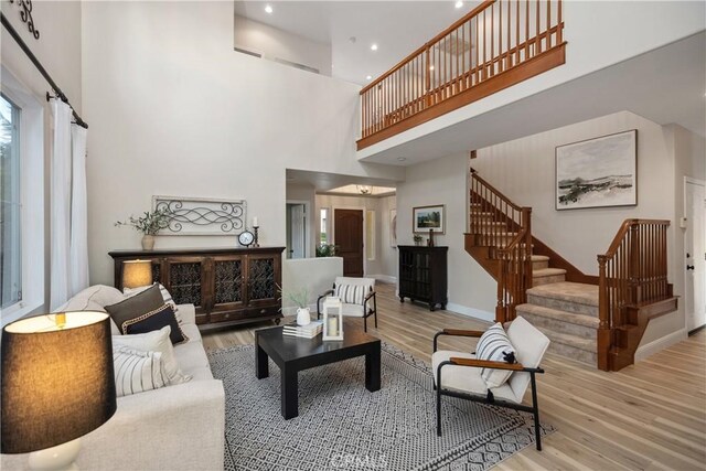 living room featuring light hardwood / wood-style flooring and a towering ceiling