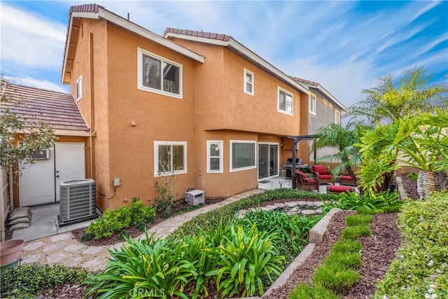 rear view of property with central AC unit, an outdoor living space, and a patio