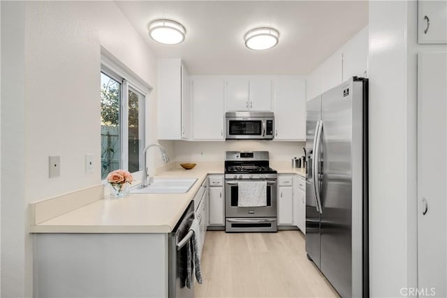 kitchen featuring appliances with stainless steel finishes, light hardwood / wood-style flooring, white cabinetry, and sink