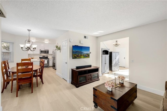 living room featuring a chandelier, a textured ceiling, light hardwood / wood-style floors, and sink