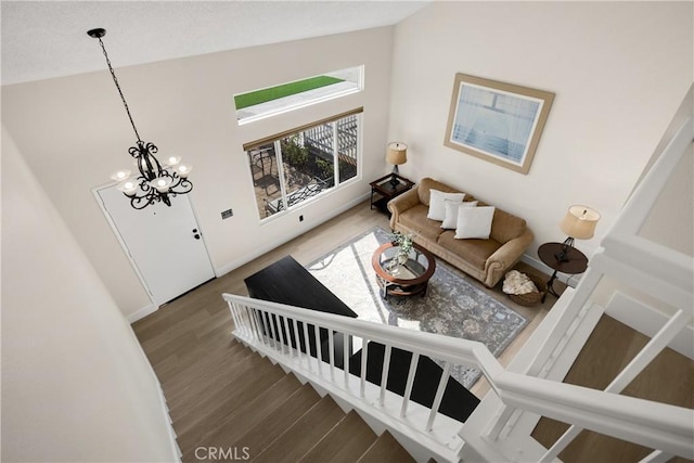 living room featuring dark hardwood / wood-style flooring, a chandelier, and vaulted ceiling