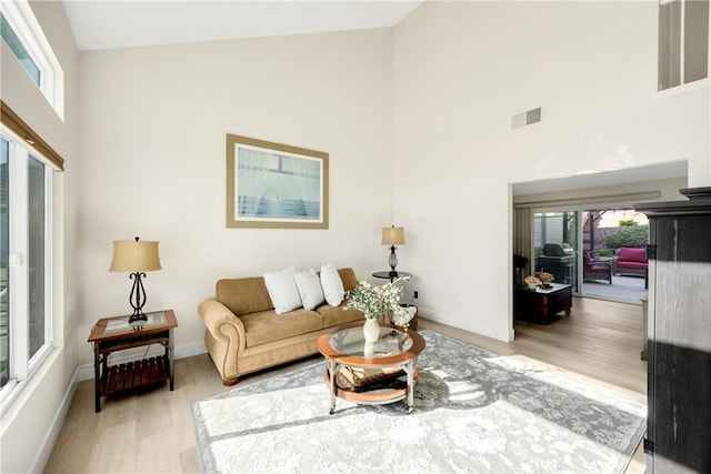 living room with high vaulted ceiling and light hardwood / wood-style floors