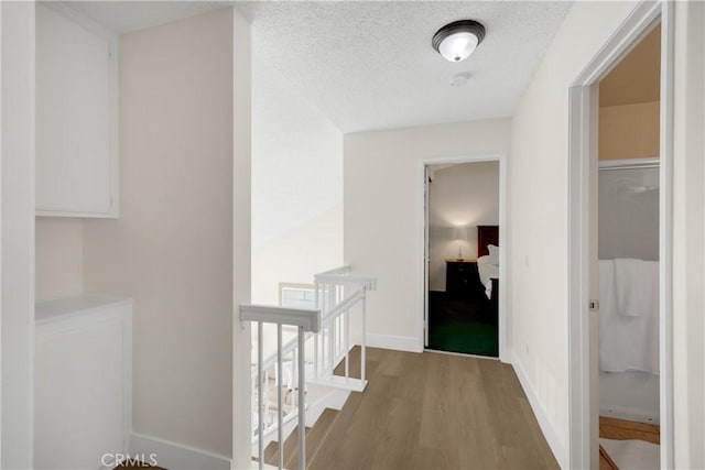 corridor with a textured ceiling and light wood-type flooring