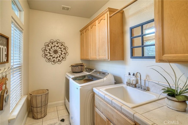 laundry area with washing machine and clothes dryer, sink, light tile patterned flooring, and cabinets