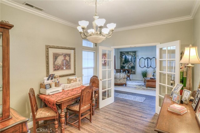 dining room featuring hardwood / wood-style floors, crown molding, french doors, and a notable chandelier