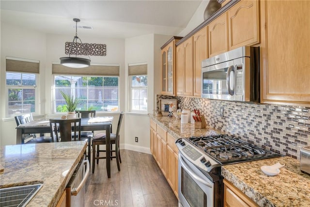 kitchen with pendant lighting, light stone counters, dark hardwood / wood-style flooring, and stainless steel appliances