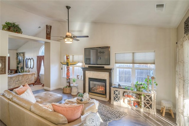 living room with a stone fireplace, ceiling fan, wood-type flooring, and lofted ceiling