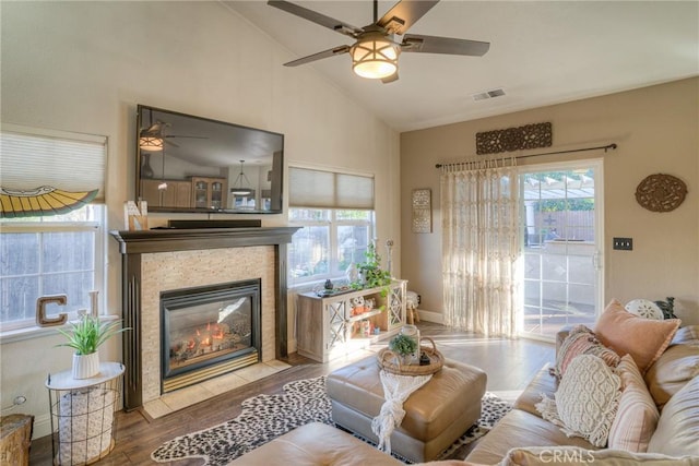 living room featuring ceiling fan, wood-type flooring, a fireplace, and vaulted ceiling