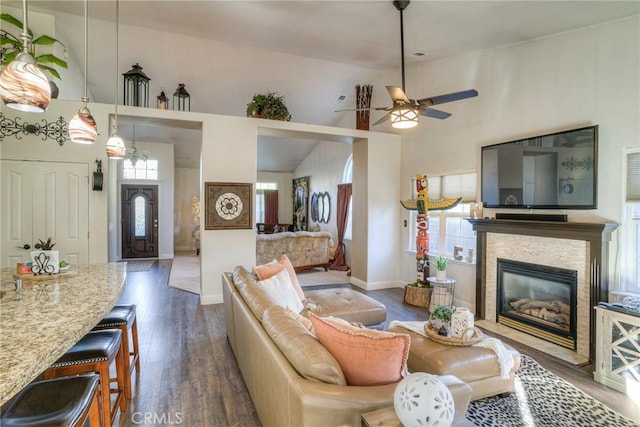 living room featuring dark hardwood / wood-style floors, ceiling fan, a stone fireplace, and a wealth of natural light